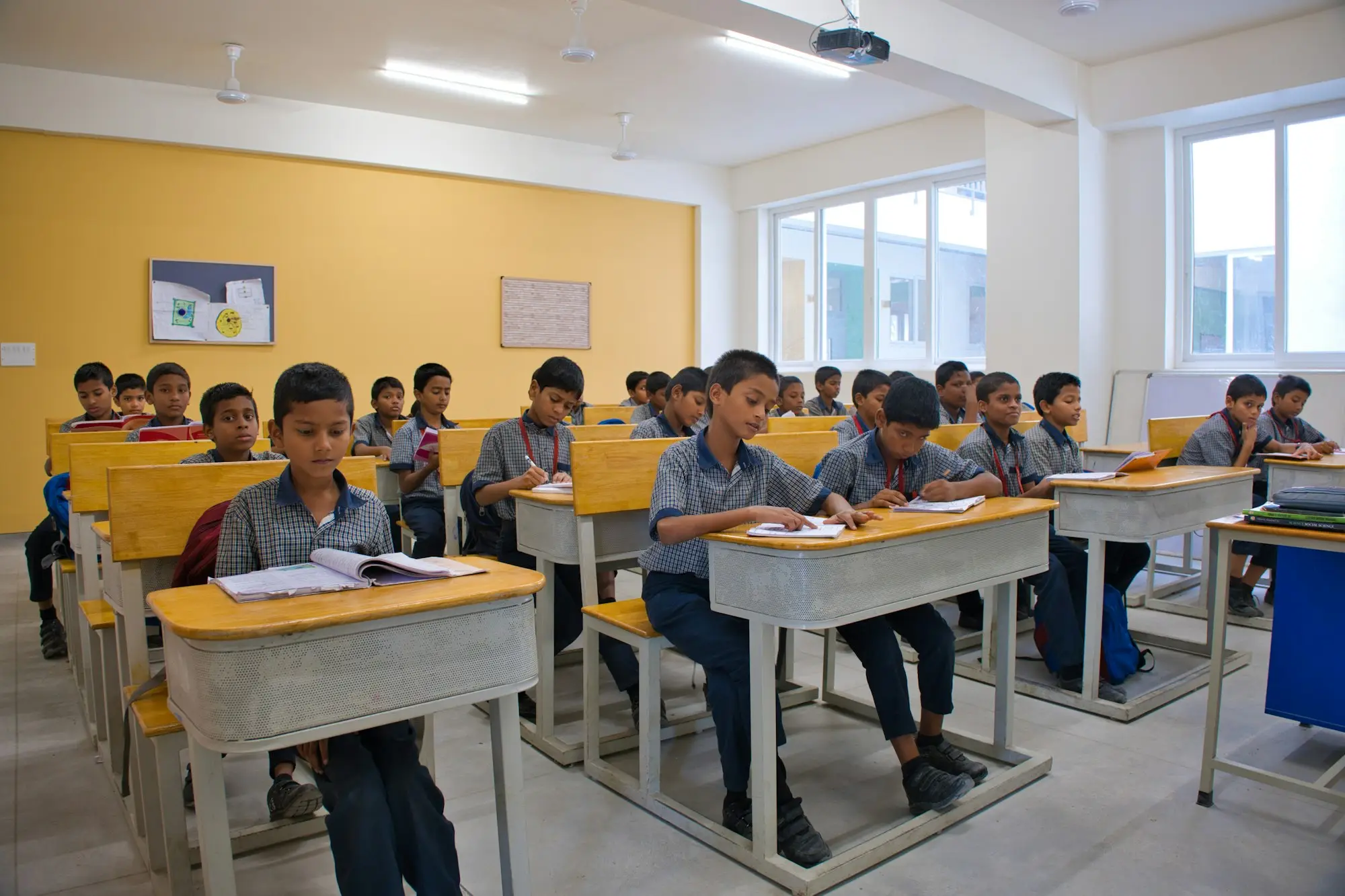 A full classroom of students at wooden desks in an Indian school