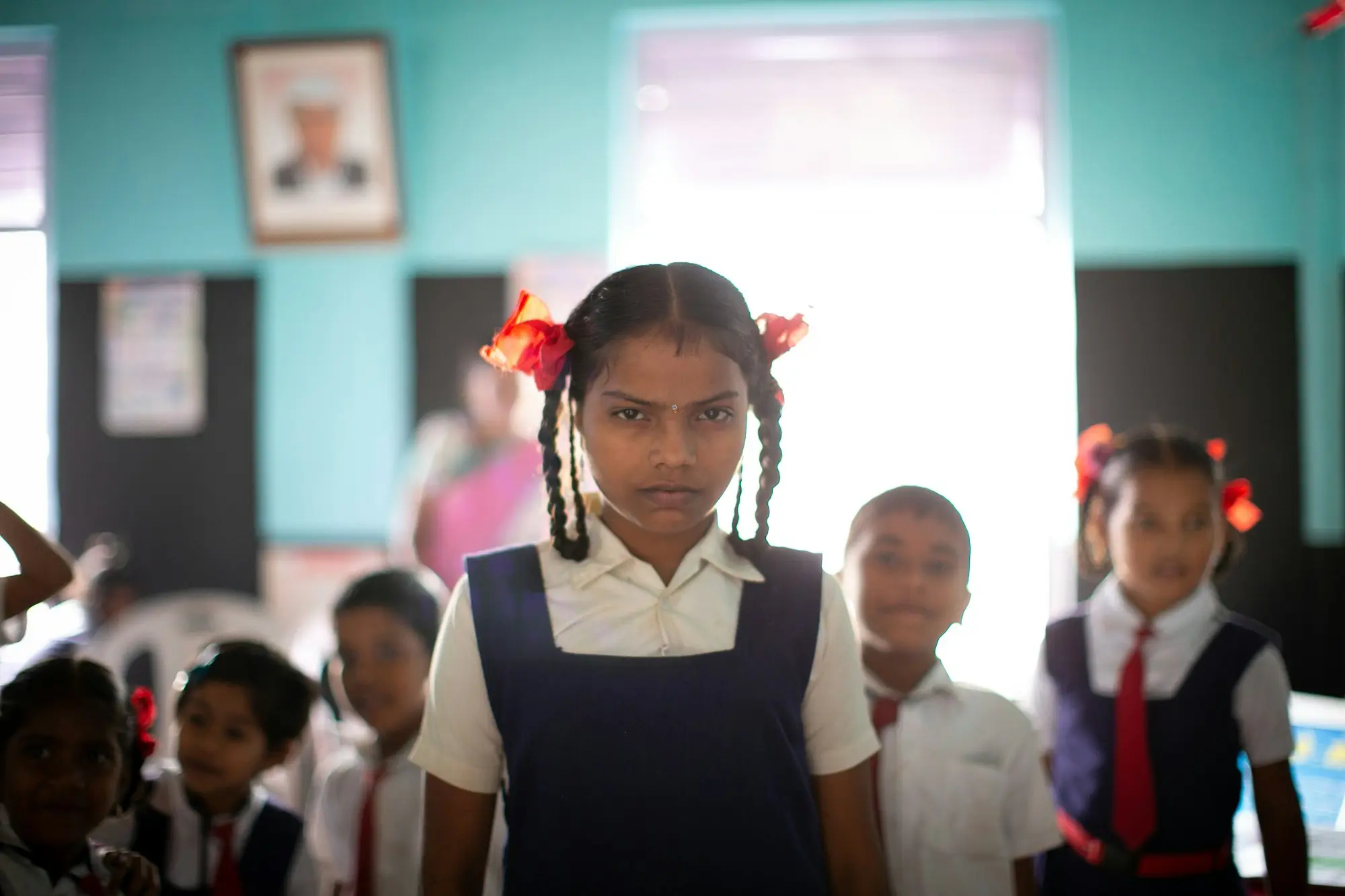 A girl in school uniform standing in a classroom doorway