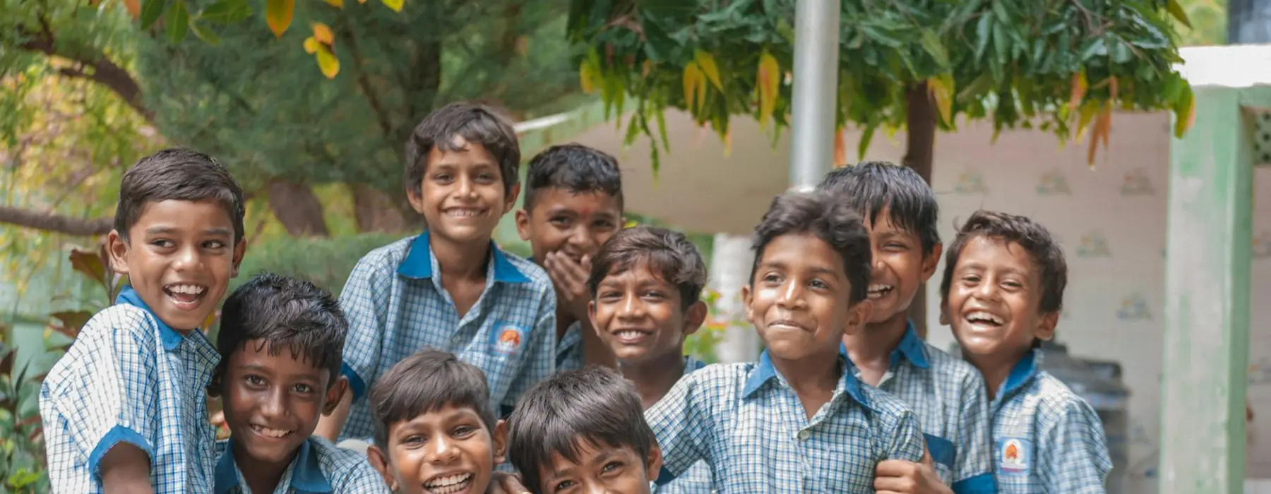 Schoolchildren in blue check uniforms standing together outside a school building