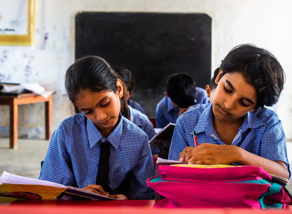 Two students in school uniform working at a desk with books open